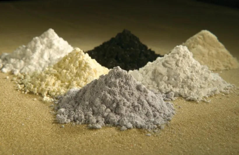Six rare earth elements of different colors, in piles of powder.